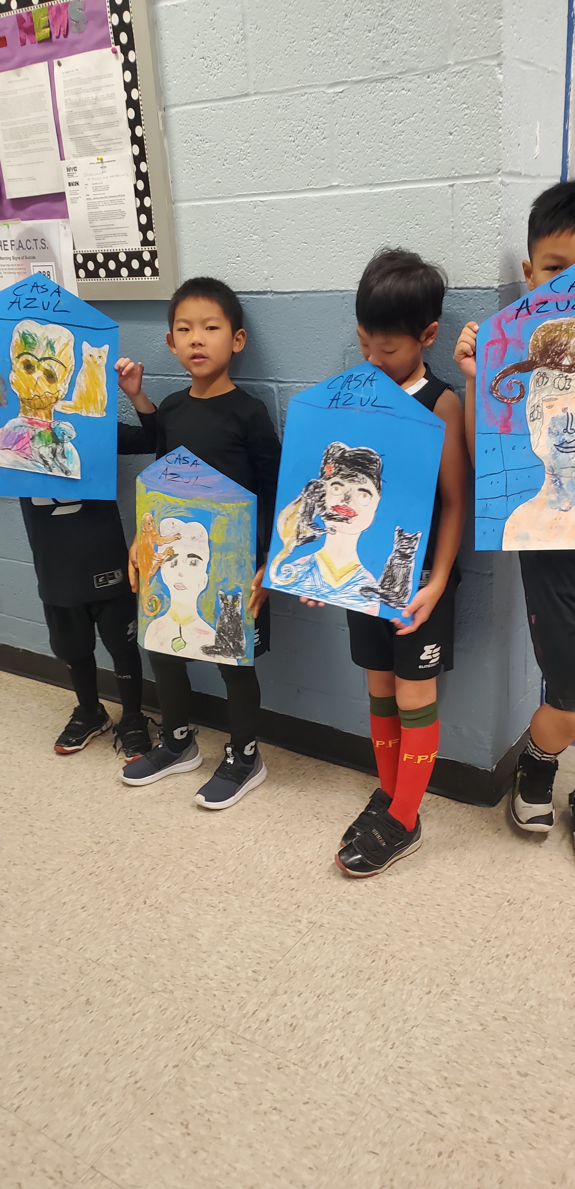 Kids holding up their finished paintings at an art party